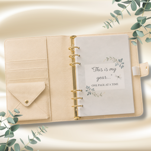February Eucalyptus Monthly Planner printable A5 PDF preview.
An open beige planner binder with gold rings, a flap pocket on the left, and a printed page that reads 'This is my year. 