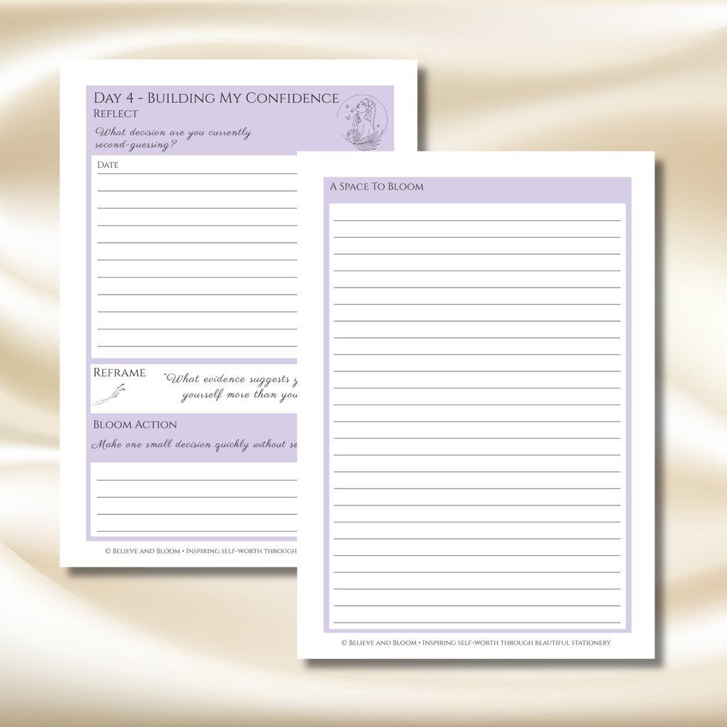 Two white notepad sheets with lavender purple headers and lined writing areas, displayed on a soft beige satin fabric background. One sheet shows reflective prompts and the other shows lined space for writing.
